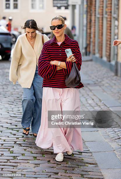 Guest wears red black striped polo shirt with long sleeves, pink skirt, brown bag outside Rave Review during Copenhagen Fashion Week day two on...
