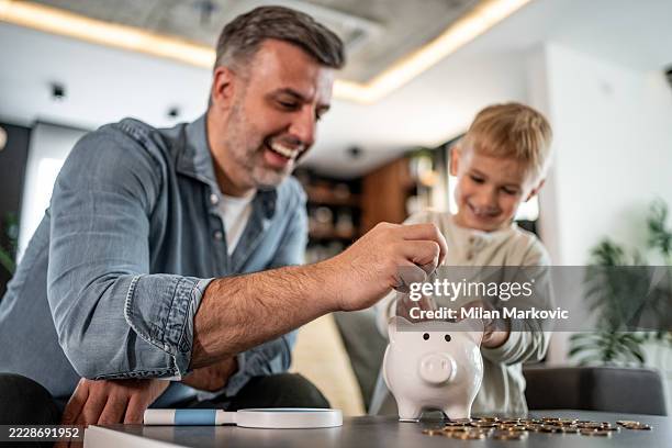 father and son saving money together in piggy bank - welvaart stockfoto's en -beelden