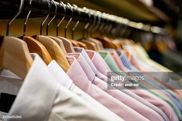 shirts hanging on the rack at a clothing store - camisa com botões imagens e fotografias de stock