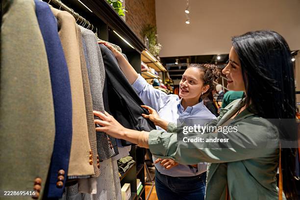 retail clerk helping a woman shopping at a clothing store - celebrity stylist stock pictures, royalty-free photos & images