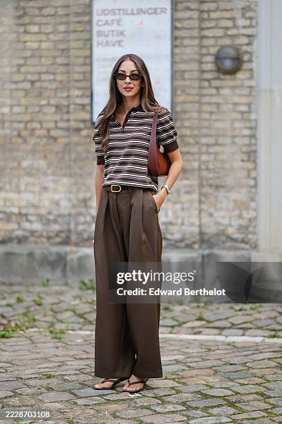 Felicia Akerstrom wears a short-sleeved polo shirt with horizontal stripes in shades of brown, white, and black. The shirt features a dark collar and...