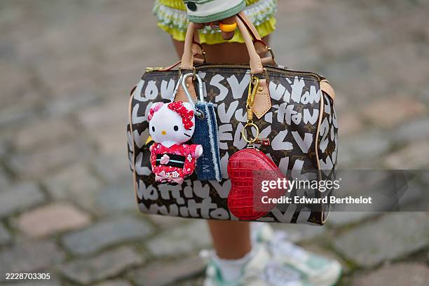 Guest wears a brown leather handbag with bold white lettering. A bag with monogram print patter in coated canvas and white painted inscriptions from...