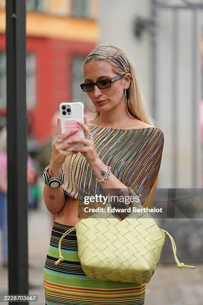 Guest wears a multicolored zigzag-patterned headband in shades of pink, green, and beige, a multicolored striped top with an asymmetrical hem,...