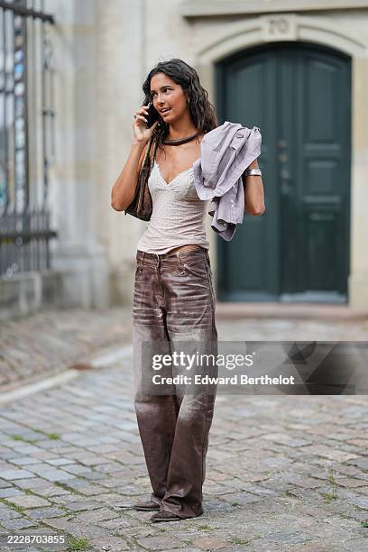 Guest wears a light pink lace-trimmed camisole with a delicate pattern, paired with wide-leg pants featuring a gradient effect from dark brown to a...