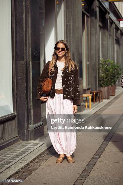 Trine Kjær wears light pink harem or genie pants, pink top, brown bag, brown belt, dark brown suede jacket with metal details and brown ballerina...