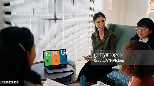 eine gruppe berufstätiger frauen sitzt in einer entspannten bürolounge und ist in ein zwangloses meeting verwickelt, bei dem es um die esg-strategie (environmental, social, governance) geht. - mitarbeiterbindung stock-fotos und bilder