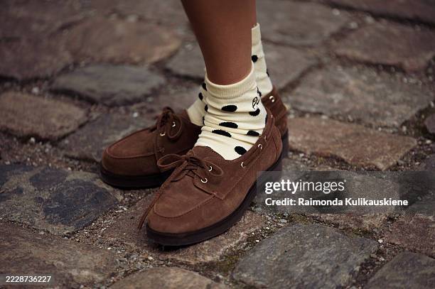 Guest wears yellow socks with black polka dots and brown loafers outside the Skall Studio show during Copenhagen Fashion Week day two on August 05,...