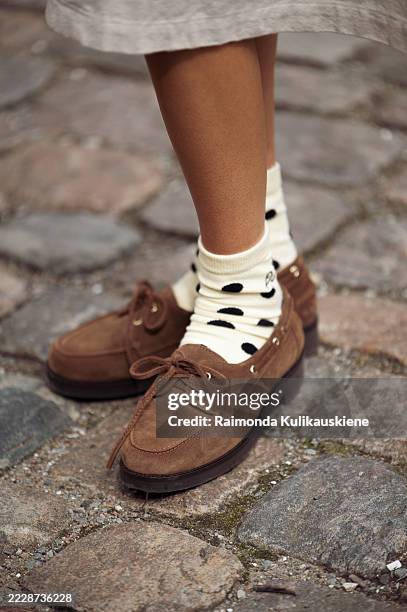 Guest wears yellow socks with black polka dots and brown loafers outside the Skall Studio show during Copenhagen Fashion Week day two on August 05,...