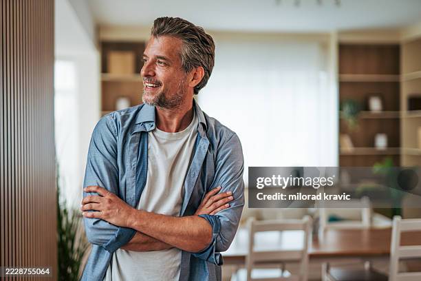 happy mature man smiling and looking away at home - home sweet home stock pictures, royalty-free photos & images