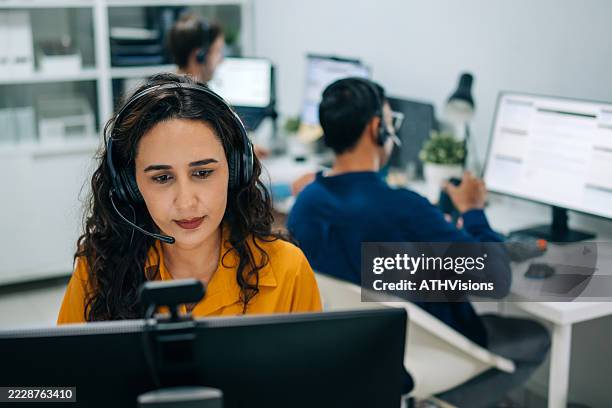 hispanic female support agent speaking clearly with a headset in a modern office. - panic button stock pictures, royalty-free photos & images
