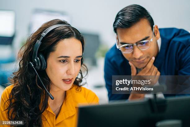customer support agents reviewing data on computer screen together - customer support call stock pictures, royalty-free photos & images