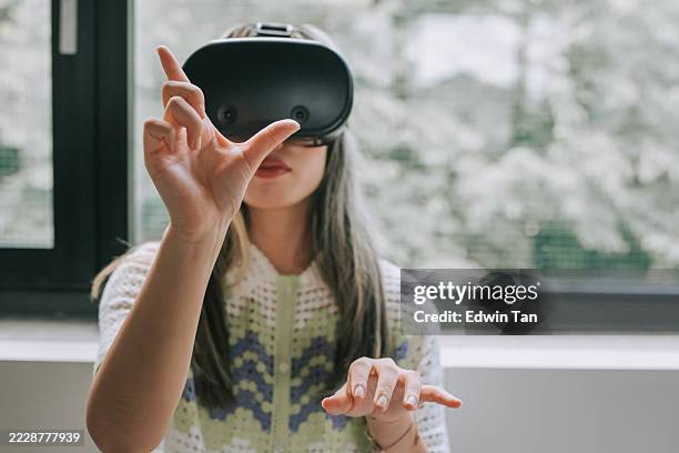 japanese woman using vr headset with hand gesture to interact with virtual interface - augmented stock pictures, royalty-free photos & images
