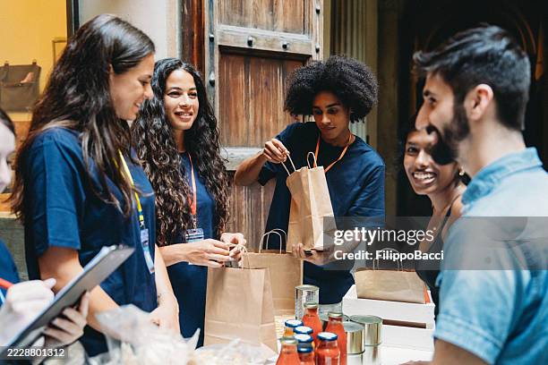 voluntarios preparando bolsas de comestibles para los beneficiarios del banco de alimentos - generosidad fotografías e imágenes de stock