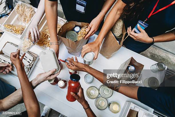 volunteers preparing grocery bags for donation to needy people - banco alimentar imagens e fotografias de stock