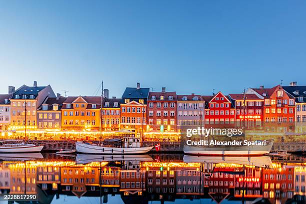 nyhavn harbour illuminated at dusk, copenhagen, denmark - copenhagen nyhavn stock pictures, royalty-free photos & images