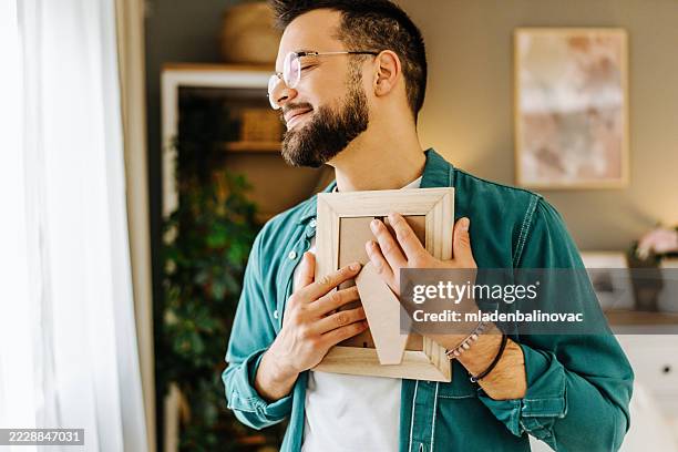 young man holding a picture frame close to his chest - artists model stock pictures, royalty-free photos & images