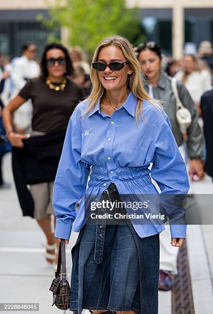 Guest wears blue blouse, denim shorts, Fendi bag outside Herskind during Copenhagen Fashion Week day three on August 06, 2025 in Copenhagen, Denmark.