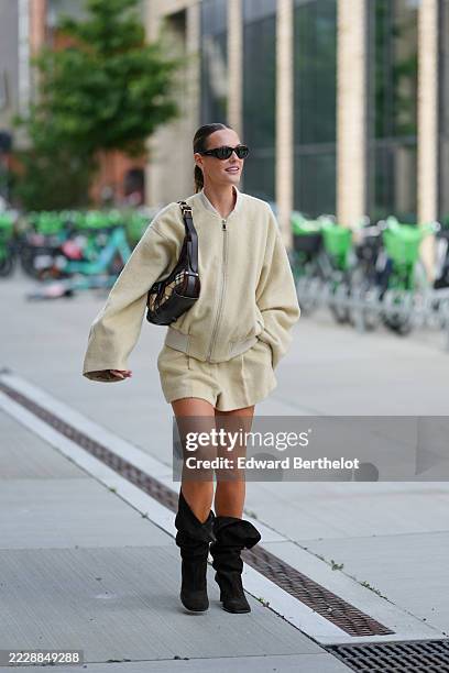 Tine Van Cauwenberghe wears a light beige oversized jacket with a zip closure and ribbed cuffs, paired with matching high-waisted shorts. Dark...