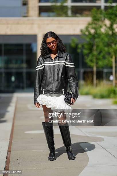 Sara Flaaen Licius wears a black leather jacket featuring white horizontal stripes across the chest and sleeves, with a front zipper closure and side...