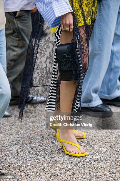 Guest wears black bag, heeled yellow flip flops outside Munthe during Copenhagen Fashion Week day three on August 06, 2025 in Copenhagen, Denmark.