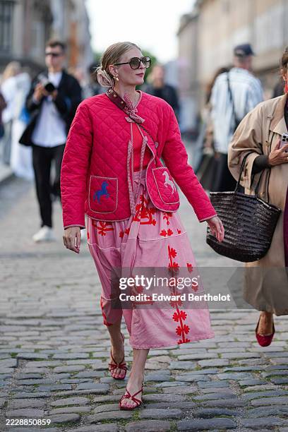 Guest wears a bright pink quilted jacket featuring two front pockets with blue and white horse motifs. The jacket is styled over a pink dress adorned...