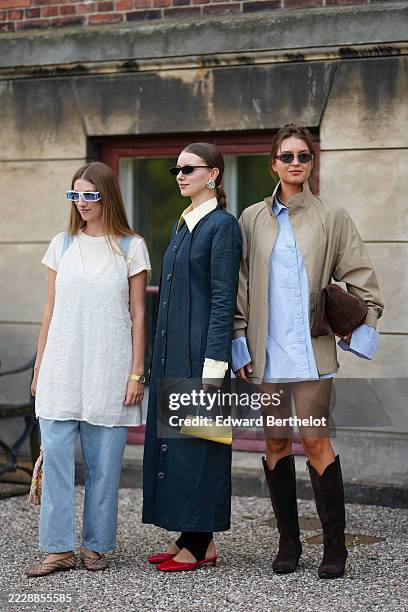Guest wears a white short-sleeve top layered under a sheer white dress with delicate embellishments. Light blue denim jeans are paired with woven...