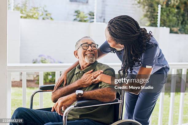 young female nurse hugging an elderly man in a wheelchair - rolstoel stockfoto's en -beelden