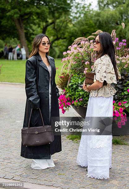 Alexandra Hoang wears black leather coat, white pants, Manu Ate brown bag & Tsutsumi Hoang wears beige blouse, white pants, brown bag outside MKDT...