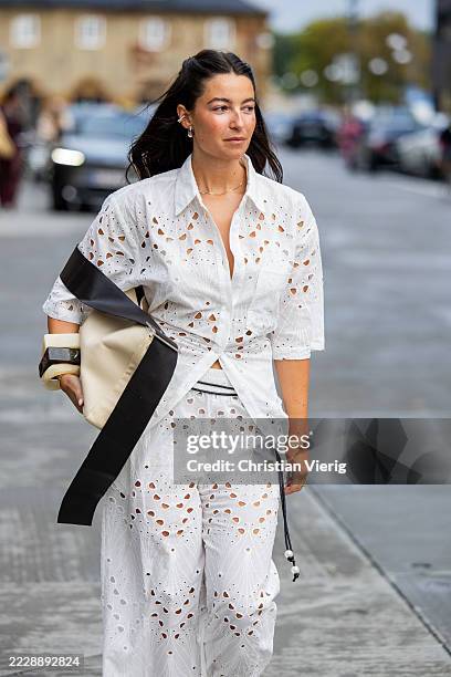 Benthe Liem wears white cut out blouse, pants, beige black bag outside Gestuz during Copenhagen Fashion Week day three on August 06, 2025 in...