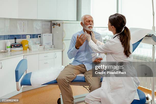 throat swelling check by caring female doctor during senior exam - lymph node stock pictures, royalty-free photos & images