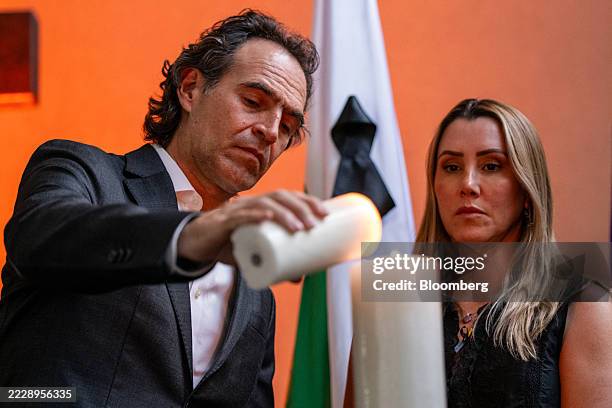 Federico Gutierrez, mayor of Medellin, left, lights a candle during a vigil for Senator Miguel Uribe Turbay, a Colombian presidential hopeful, in...