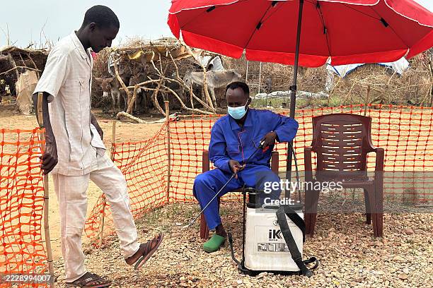 Worker disinfects a man at the entrance of a cholera isolation centre at the refugee camps of western Sudan, in Tawila city in Darfur, on August 12,...