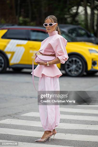 Nina Sandbech wears pink cropped top, skirt, pants, Jil Sander bag, sunglasses, heels outside Marimekko during Copenhagen Fashion Week day four on...