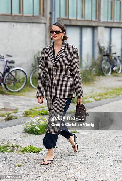 Mary L. Jean wears checkered blazer, two tone denim jeans, brown bag, sunglasses outside Marimekko during Copenhagen Fashion Week day four on August...
