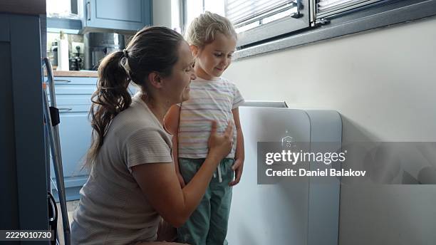 intelligentes zuhause. mutter bringt kind bei, intelligente heizungssteuerung zu verwenden - wärmepumpe stock-fotos und bilder