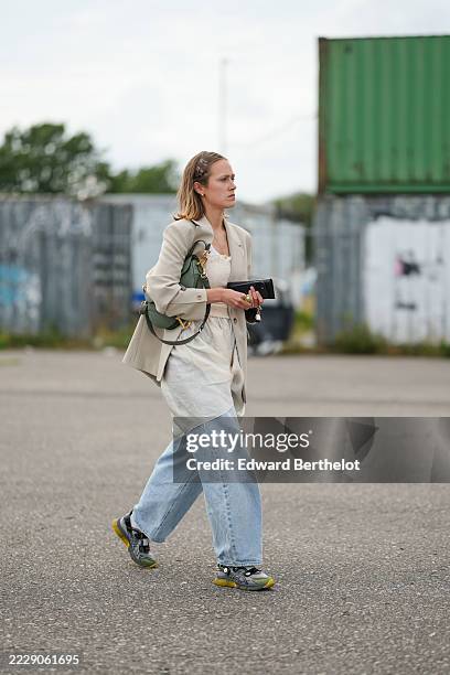 Guest wears shoulder-length straight light brown hair parted slightly to the side and tucked behind the ears, small gold hoop earrings, and a light...