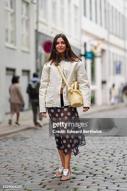 Guest wears long dark brown hair worn down in a center part with a smooth finish and understated natural makeup, then an off-white cotton canvas...