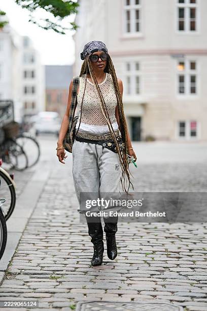 Guest wears long honey-blonde box braids worn loose from under a black-and-white paisley bandana headscarf, oversized square black sunglasses,...