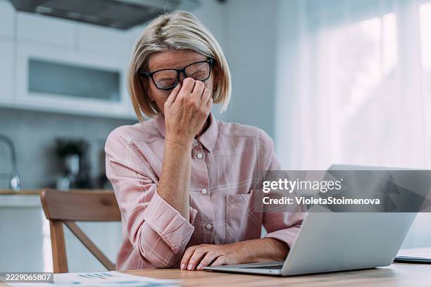 mujer de negocios estresada que usa computadora portátil en casa. - manos a la cabeza fotografías e imágenes de stock