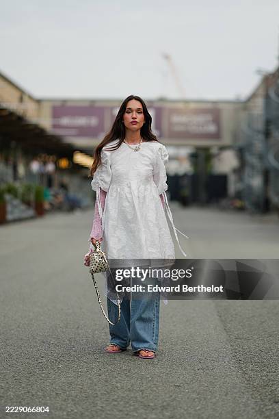 Guest wears a white textured tunic with gathered sleeves and tie details, layered over a pink lace long-sleeve top. A necklace with a floral pendant...