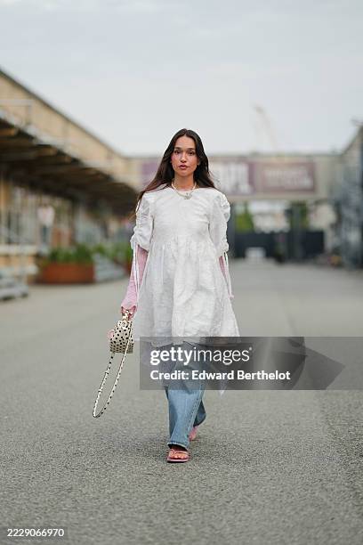 Guest wears a white textured tunic with gathered sleeves and tie details, layered over a pink lace long-sleeve top. A necklace with a floral pendant...