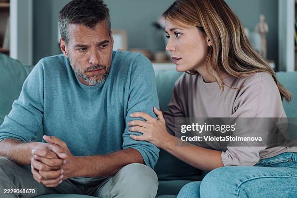 besorgtes paar, das sich zu hause im wohnzimmer unterhält. - unehrlichkeit stock-fotos und bilder