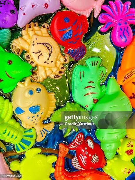 full frame close-up of assorted multi coloured marine animal shaped toys floating in water - animal shell stock pictures, royalty-free photos & images