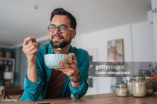 giovane che si gode una sana colazione a casa - cereali da colazione foto e immagini stock
