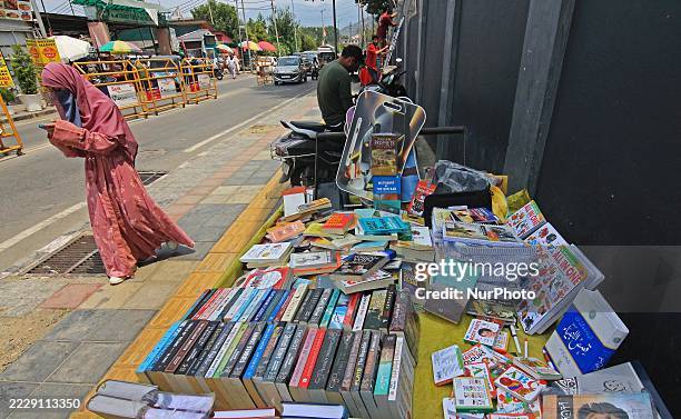 Woman walks past a hand-cart that displays books in Srinagar, Kashmir, India, on August 12, 2025. The government of Jammu and Kashmir bans the sale,...