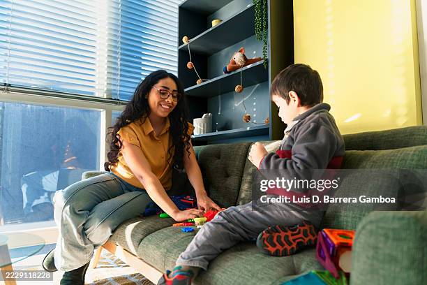 latin american babysitter playing with child on sofa - nanny stock pictures, royalty-free photos & images