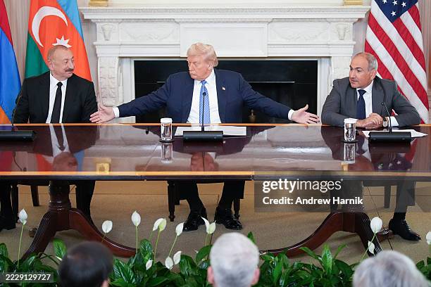 President Donald Trump reaches out to join hands with Azerbaijani President Ilham Aliyev and Armenian Prime Minister Nikol Pashinyan during a signing...
