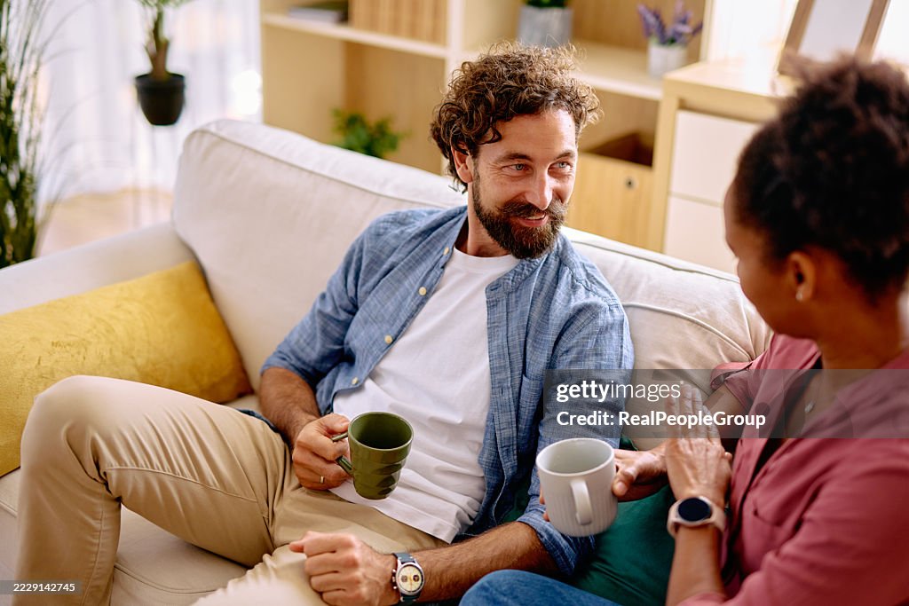 Paar entspannt sich auf dem Sofa, trinkt Kaffee und redet zu Hause