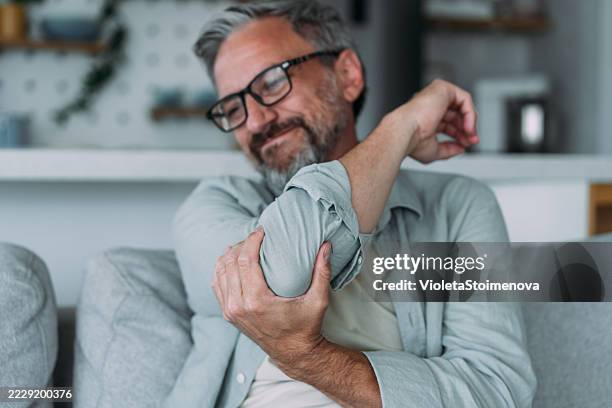 l'uomo si massaggia la mano con dolore al gomito. - gotta foto e immagini stock