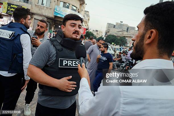 Journalist in a press vest speaks to a reporter during a solidarity stand in Idlib, Syria on August 11, 2025. The demonstration condemns the...